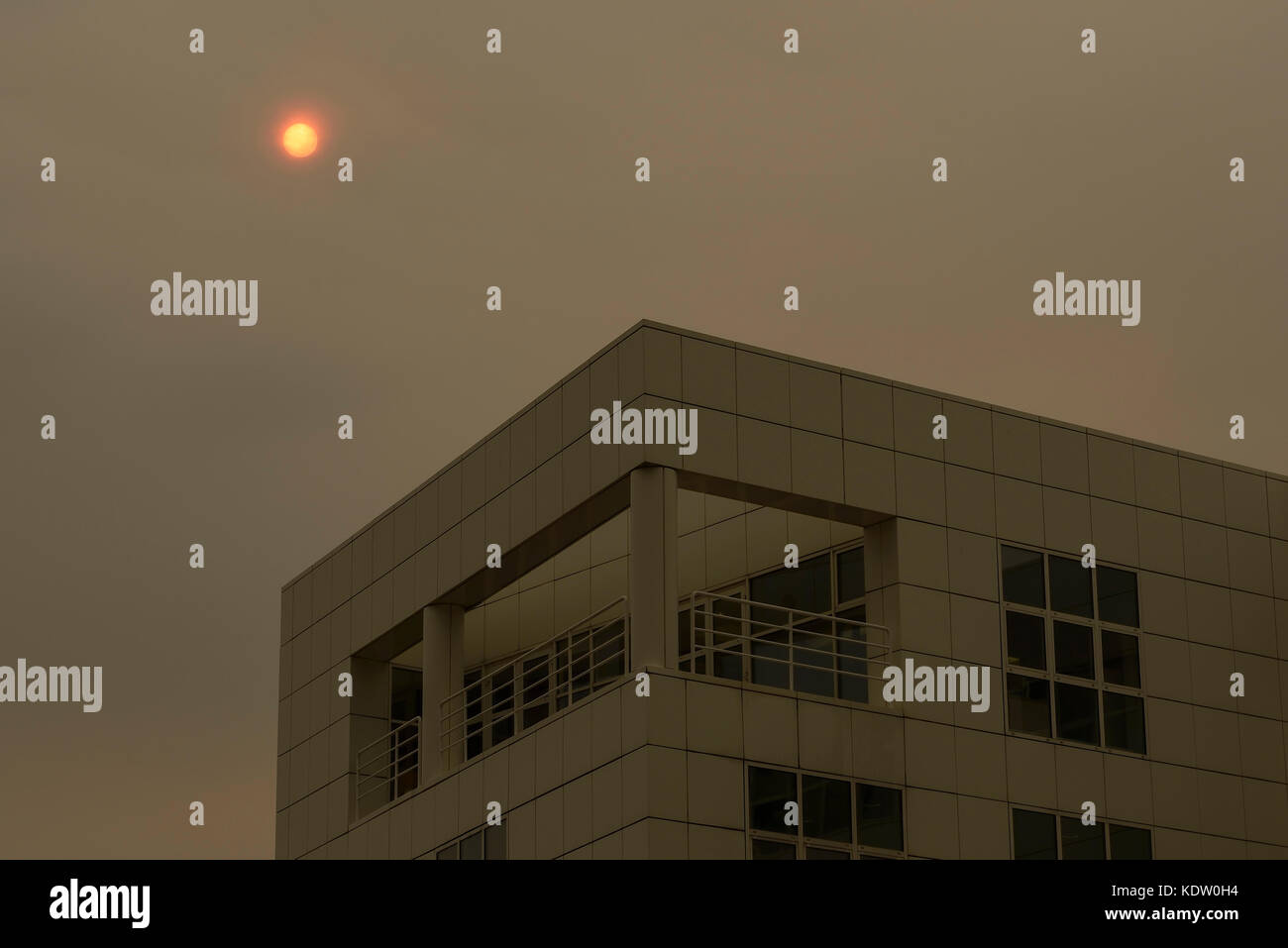 Manchester, UK. 16 Oct, 2017. Un soleil rouge apparaît derrière un immeuble de bureaux avec une couleur inhabituelle qui semble être causé par la poussière du Sahara. Crédit : Andrew Paterson/Alamy Live News Banque D'Images