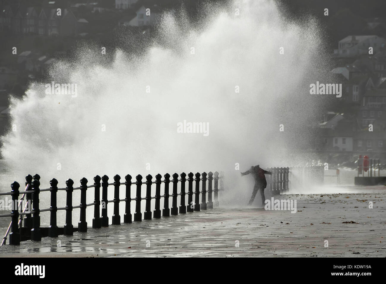 Penzance, Cornwall, UK. 16 octobre 2017. Météo britannique. Un tressaillement cherche femme obtient un trempage comme elle se tient en face d'une vague d'éclaboussures qui a frappé la promenade à Penzance en Cornouailles, qui a été attisé par des coups de vent de l'ouragan Ophelia ex. Crédit photo : Graham Hunt/Alamy Live News Banque D'Images