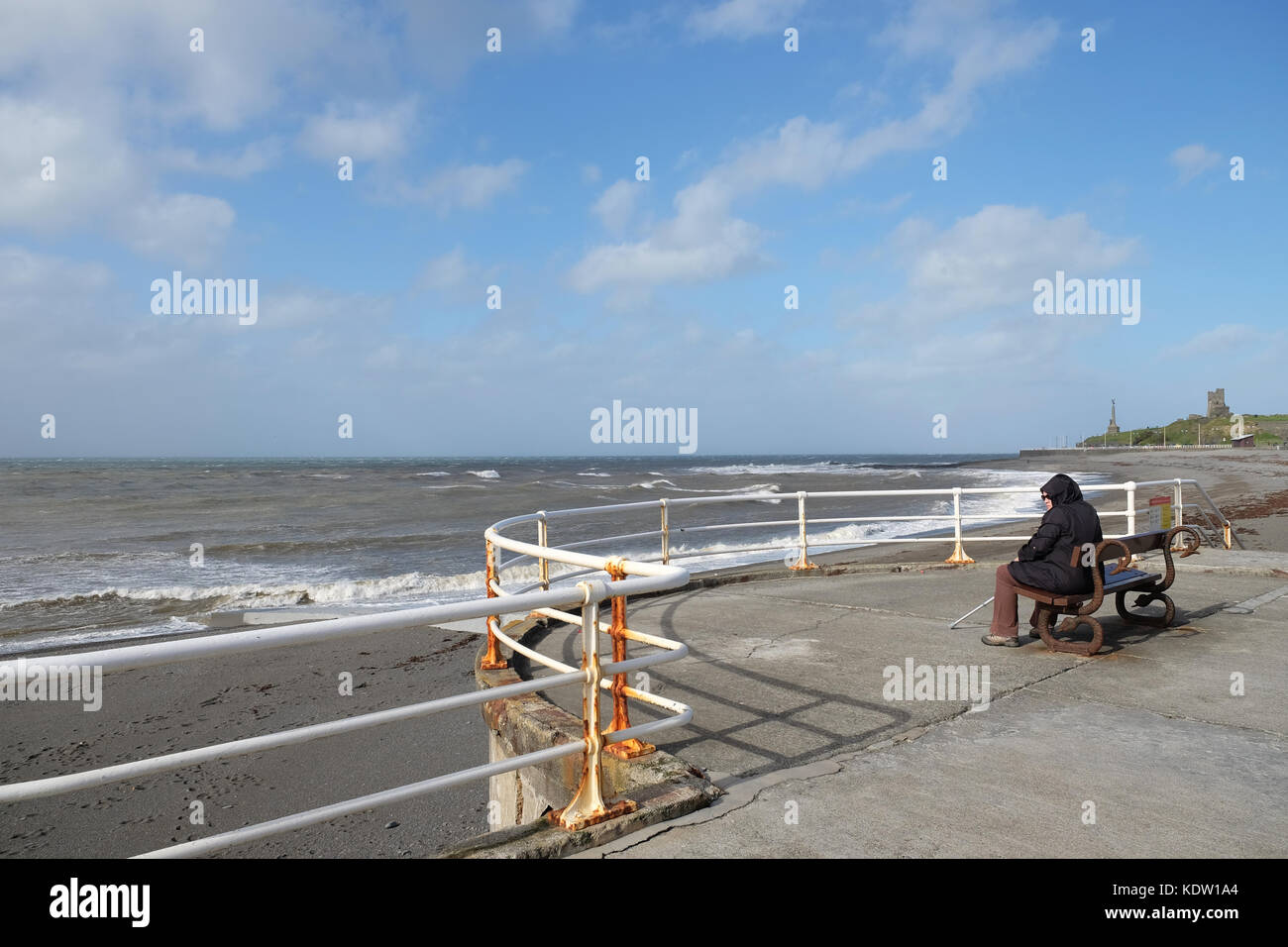 Aberystwyth, Ceredigion, pays de Galles, Royaume-Uni. 16th octobre 2017. Météo Royaume-Uni. Une femme s'assoit et regarde les vents forts de plus de 50mph sur la plage à Aberystwyth - les vents forts viennent du sud-ouest à travers la mer d'Irlande sur la côte ouest du pays de Galles, à l'approche de Storm Ophelia - photo Steven May / Alamy Live News Banque D'Images