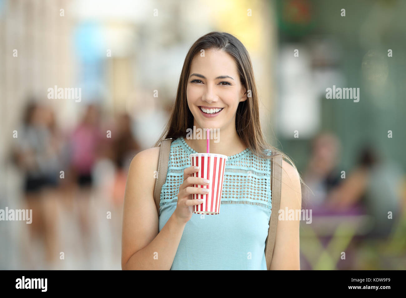 Portrait avant d'une jeune fille tenant une boisson à emporter et à la caméra dans la rue à Banque D'Images