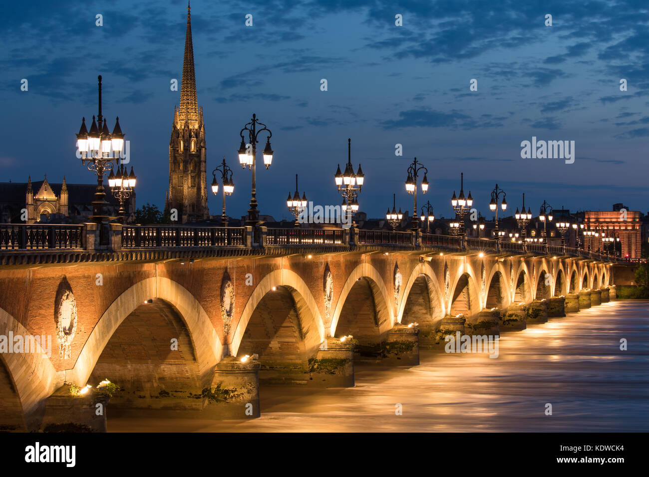 Pont de pierre enjambant le fleuve Garonne au crépuscule avec basilique Saint-Michel au-delà, Bordeaux, Aquitaine, France Banque D'Images