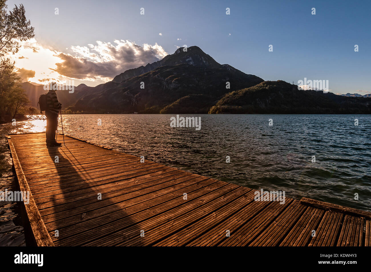 Randonneur debout sur dock sur le lac de fin. Tramper à coucher de soleil sur le lac. Banque D'Images