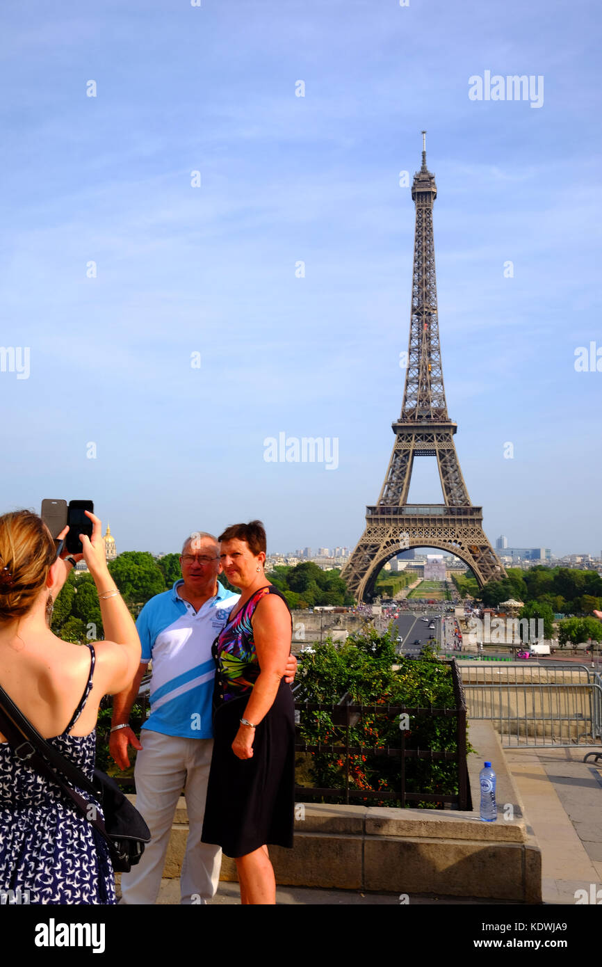 Un couple d'âge mûr ont leur photo sur un smartphone en face de la Tour Eiffel à Paris Banque D'Images