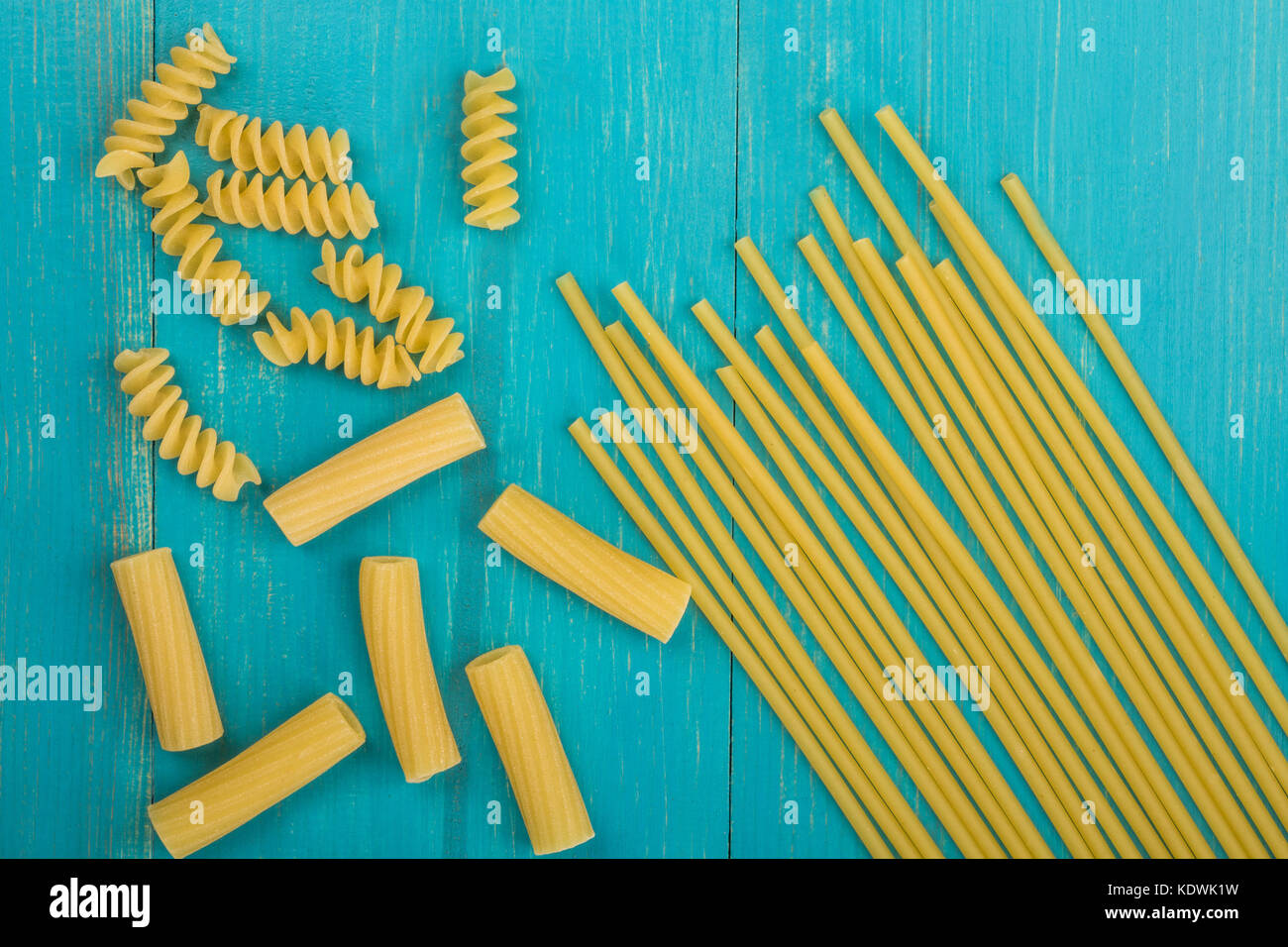 Sélection des matières style italien spaghetti pâtes non cuites et les fusilli rigatoni avec copie espace bleu sur un fond de bois Banque D'Images