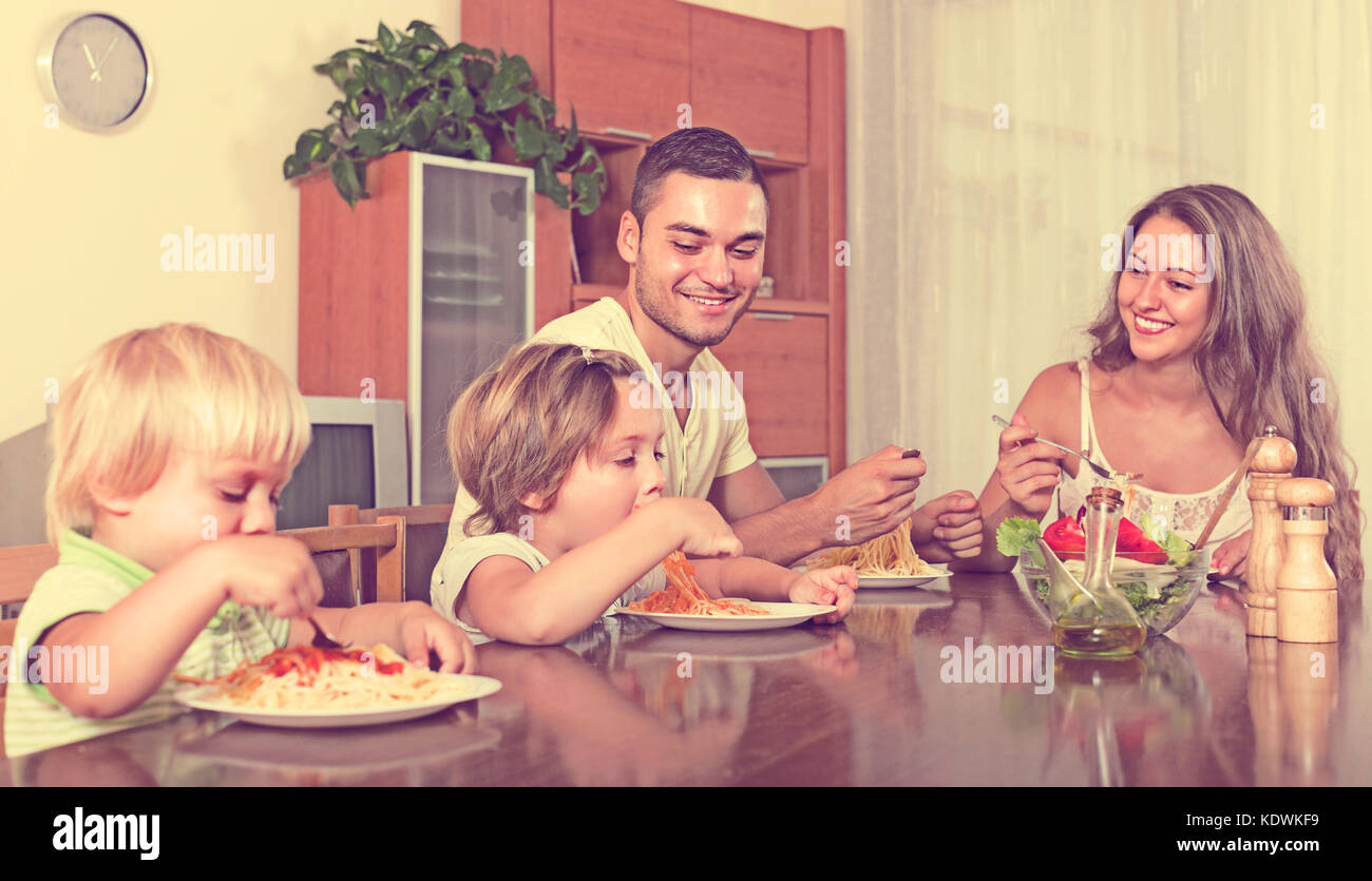 Young smiling family de quatre mange du spaghetti à la maison de l'intérieur. se concentrer sur l'homme Banque D'Images