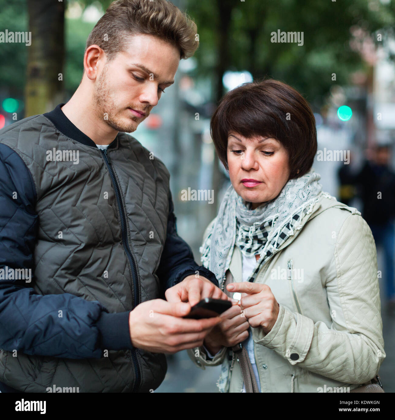 Jeune homme séropositif points la direction avec smartphone à la ville Banque D'Images