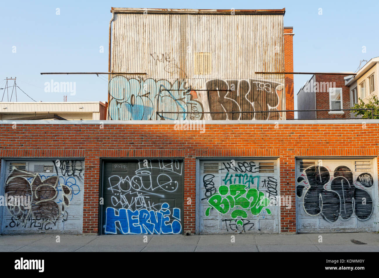 Portes de garage et un bâtiment dégradé en milieu urbain couvert de graffitis et tags, Montréal, Québec, Canada Banque D'Images