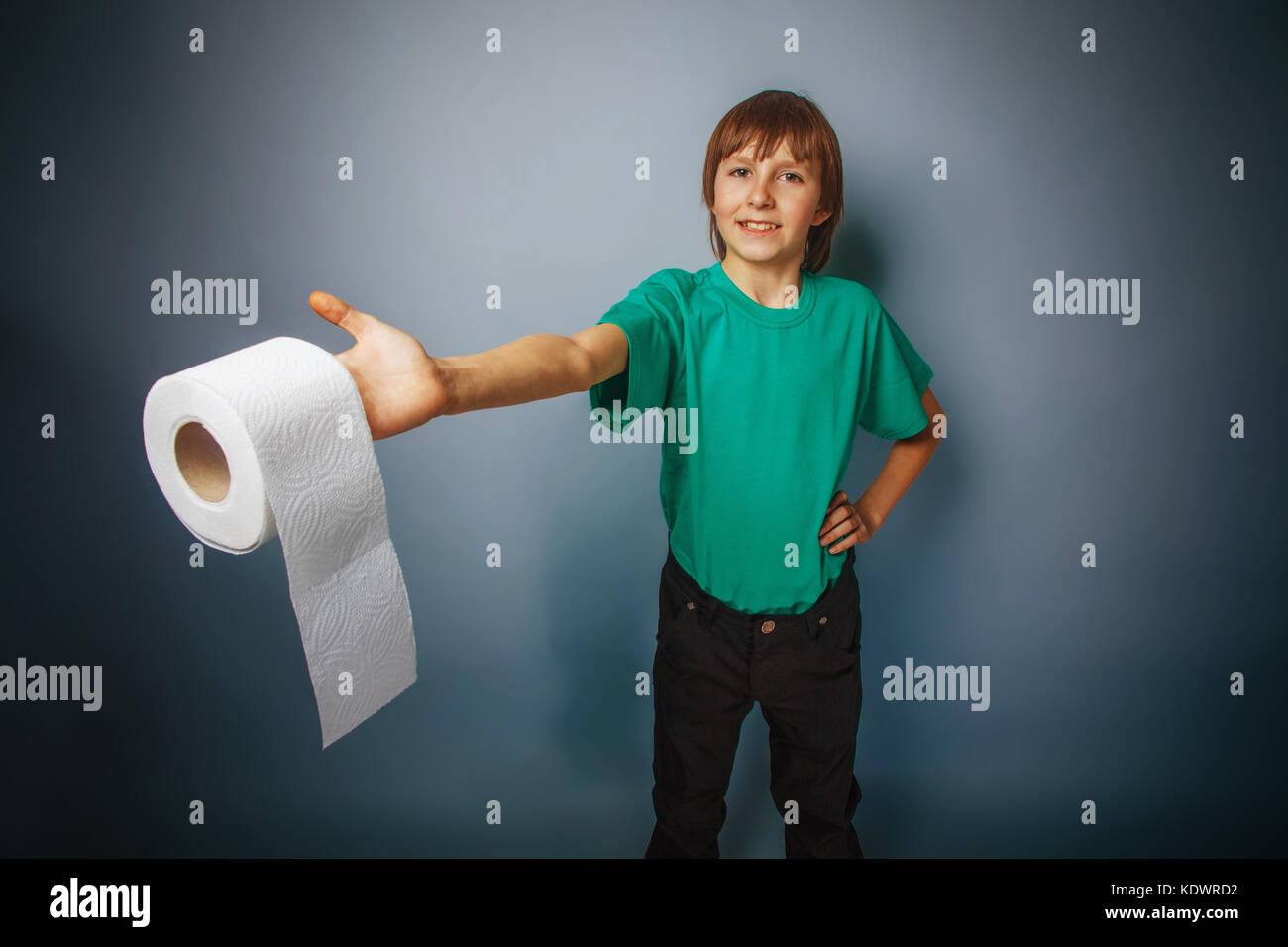 L'apparence de l'adolescent garçon cheveux brun dans une chemise dans sa main tenant un rouleau de papier toilette sur un fond gris traitement croisé Banque D'Images