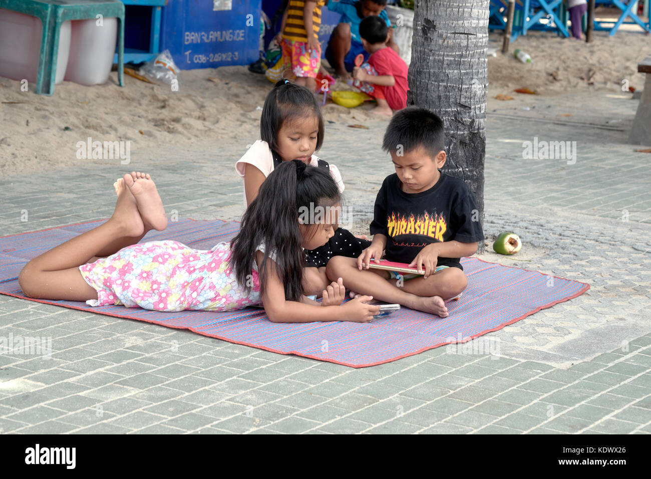 Les enfants jouent dehors avec les smartphones et tablettes iPad Banque D'Images