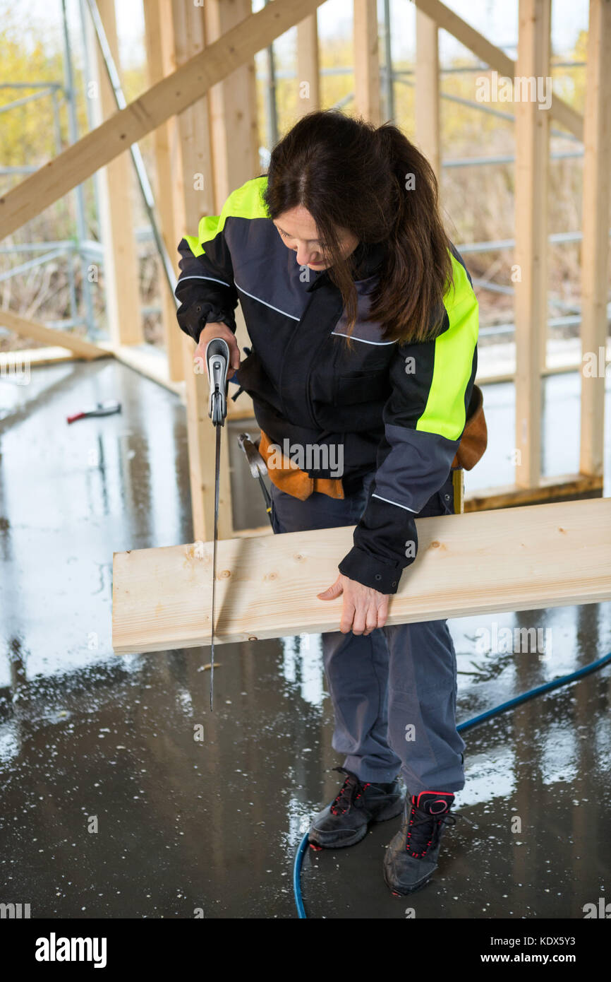 Toute la longueur de female carpenter couper du bois avec scie à main at construction site Banque D'Images