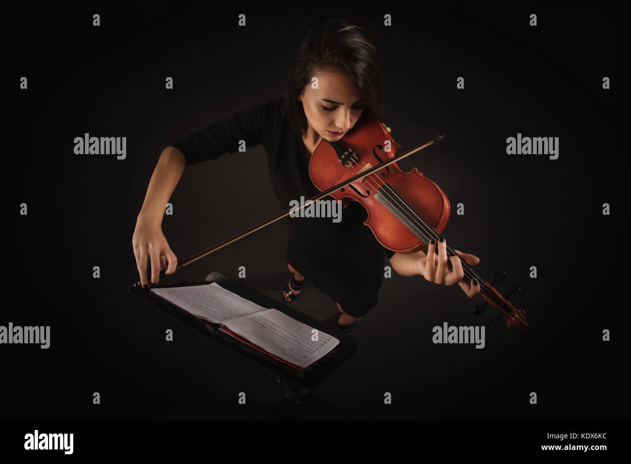 Belle femme violoniste au violon sur fond noir Banque D'Images