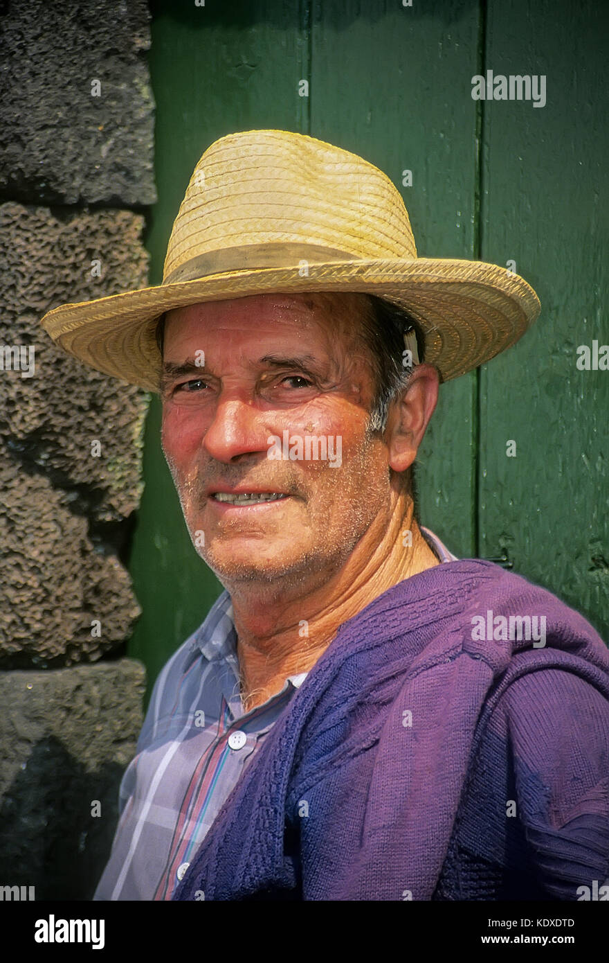 Portrait d'un agriculteur des portant un chapeau de paille traditionnel, jaune. Sa cigarette roulée à la main est à l'aide d'une cosse de maïs. L'île de Pico, Açores. Banque D'Images