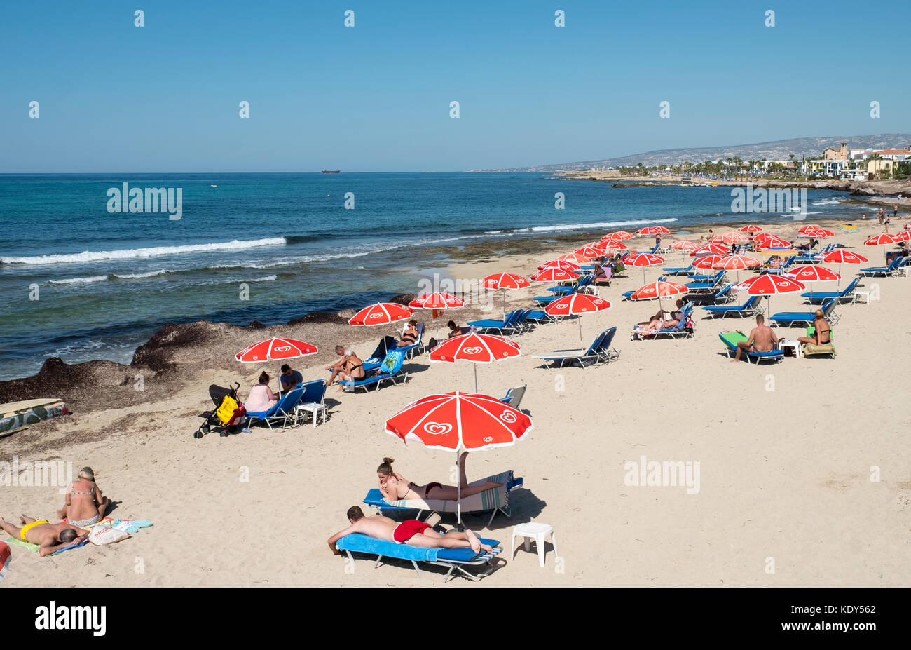 Les vacanciers se prélasser au soleil sur la plage de Kath Municipal de Paphos, Chypre. Banque D'Images