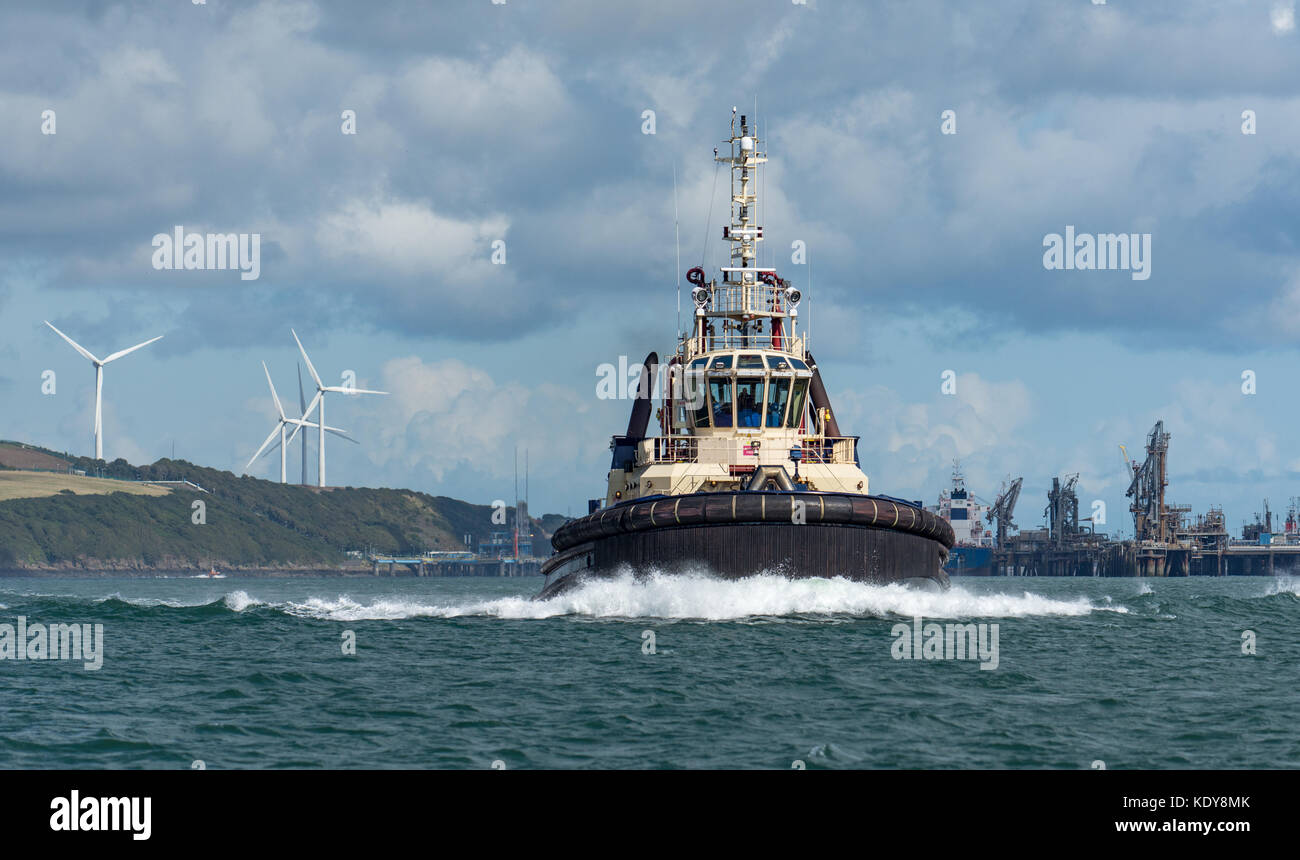 Un remorqueur puissant crée une énorme vague de proue comme il se dirige au-delà du terminal pétrolier de valero aux éoliennes en arrière-plan, de ralentir pour un yacht de luxe Banque D'Images