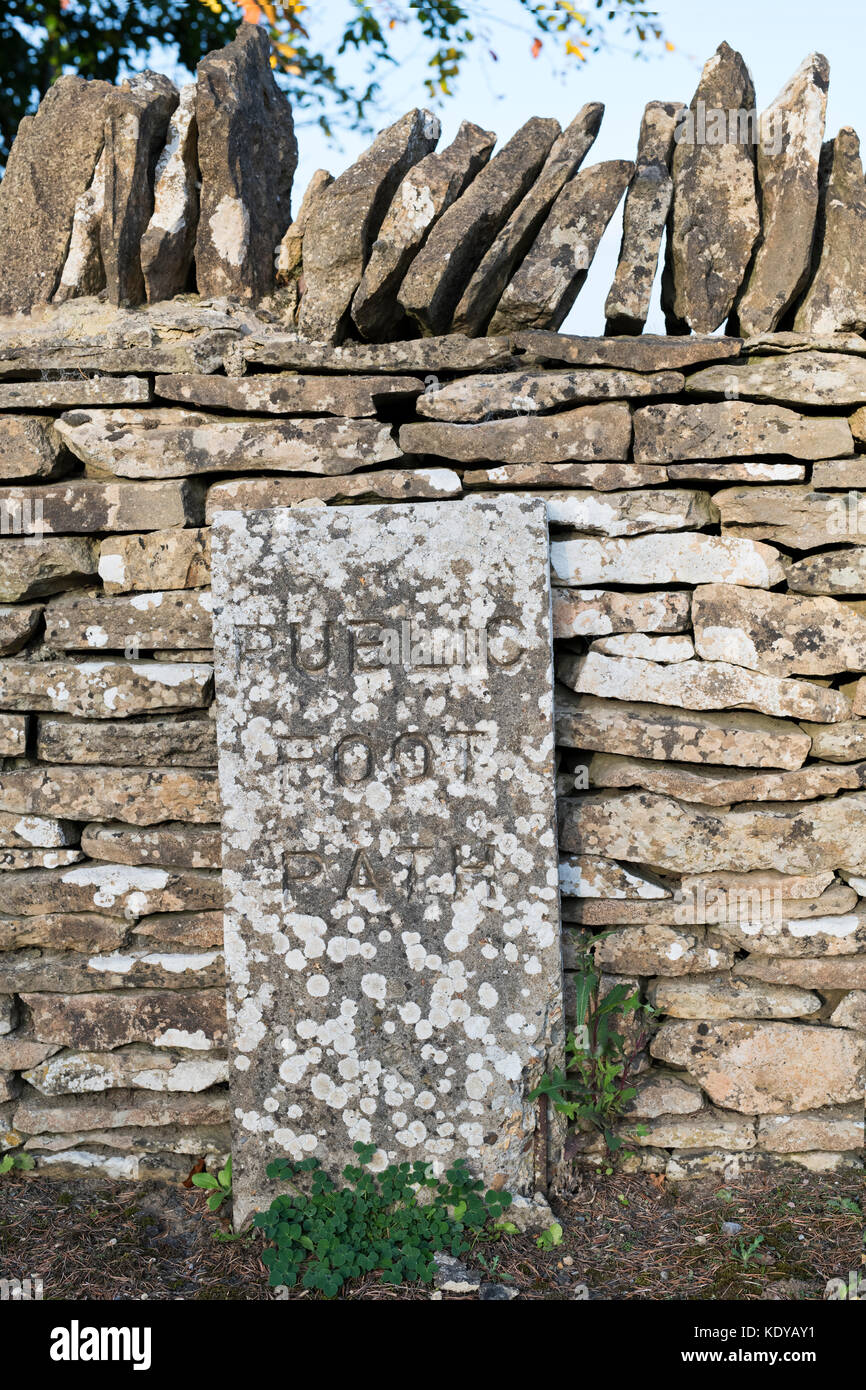 Sentier Public signe et stille dans un mur en pierre sèche, Nr Naunton, Cotswolds, Gloucestershire, Royaume-Uni Banque D'Images