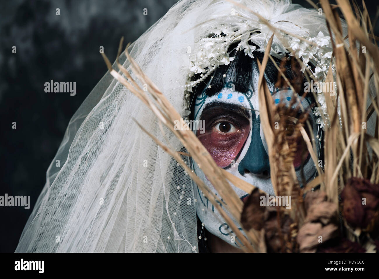 Portrait d'une jeune mariée avec un comté du maquillage, le port de voile et diadème, tenant un bouquet de fleurs fanées Banque D'Images