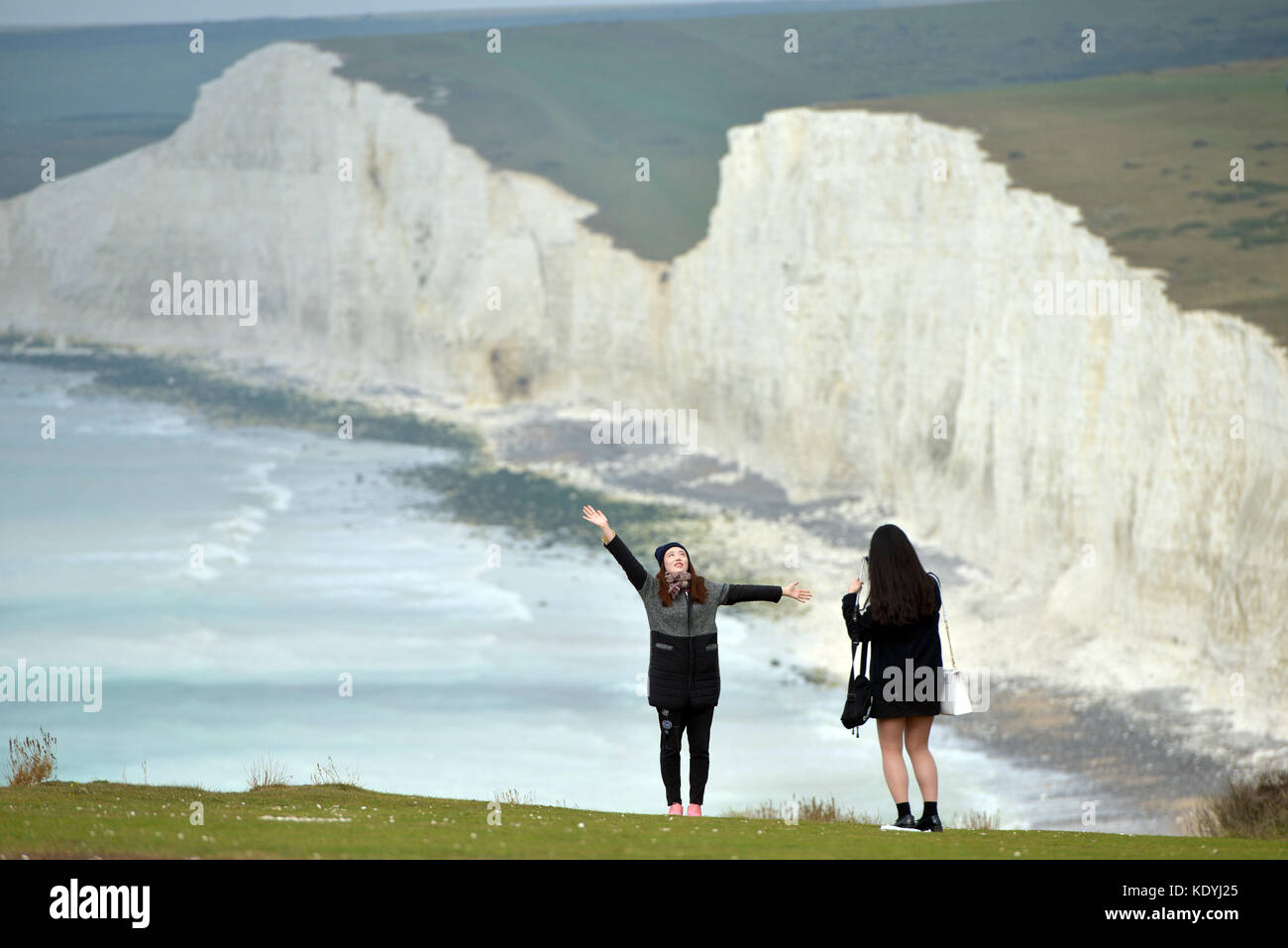 Les touristes qui risquent leur vie pour les autoportraits sur l'effondrement des falaises de craie à Urrugne, près de l'emblématique des sept Sœurs, East Sussex. Banque D'Images