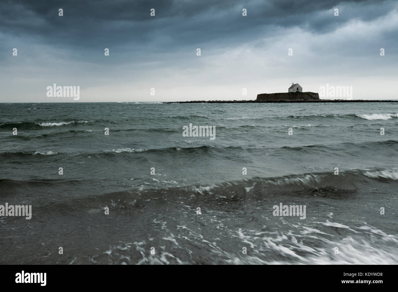 L'église St cwyfan isolé sur l'horison de la mer d'Irlande que storm ophelia fait touché terre sur Anglesey, au nord du Pays de Galles, Royaume-Uni Banque D'Images