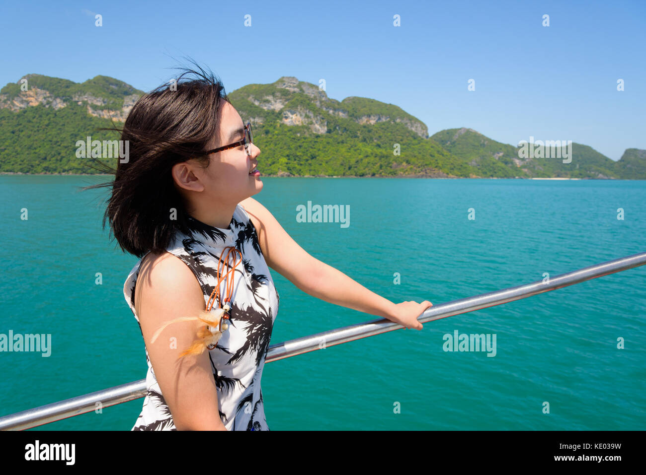 Cute young woman with eyeglasses smiling joyeusement sur le bateau lors d'une croisière sur le magnifique paysage naturel de la mer bleue et le ciel en été à mu ko Ang Thong Banque D'Images