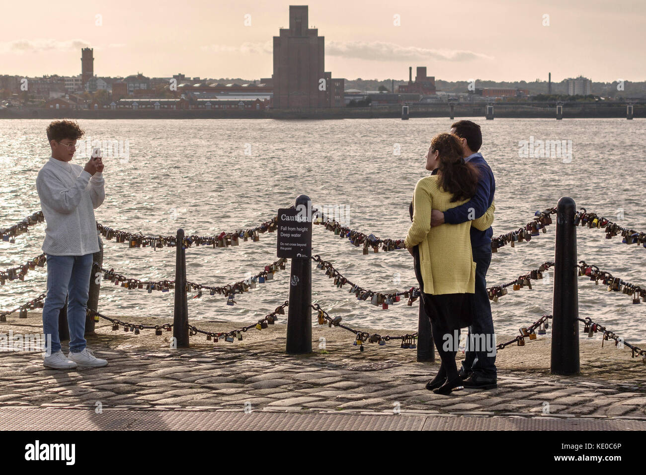 Pier Head, Liverpool, Royaume-Uni. Un couple ont leur photo prise à côté de la rivière Mersey. Les rampes sont couverts avec des Banque D'Images