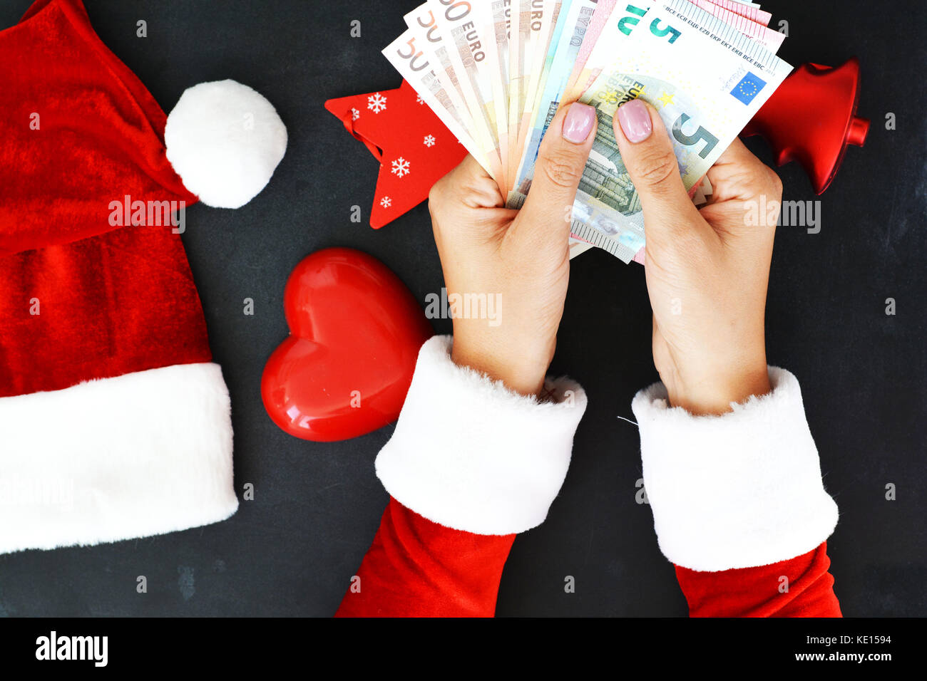 Femme avec le costume de Père Noël avec des billets en euros en espèces, ce qui suggère des dépenses de vacances Banque D'Images