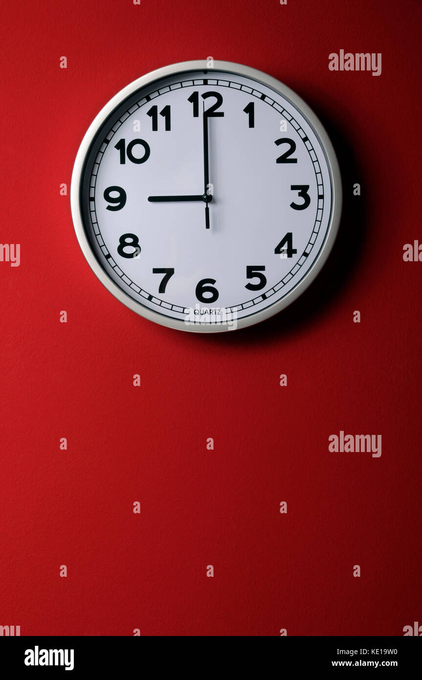 Horloge murale sur fond rouge montrant 9 o vertical de l'horloge Banque D'Images