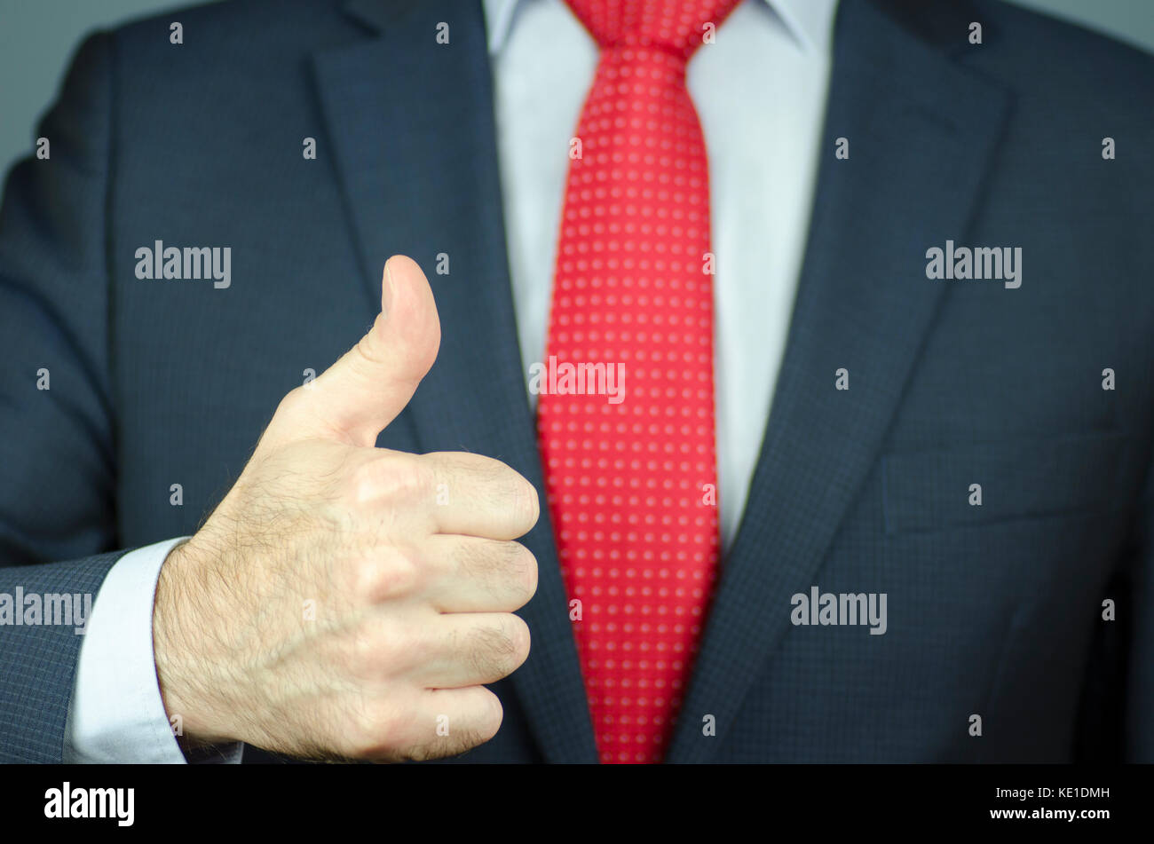 Une vue rapprochée d'un manager dans un costume et une cravate rouge avec thumb up Banque D'Images