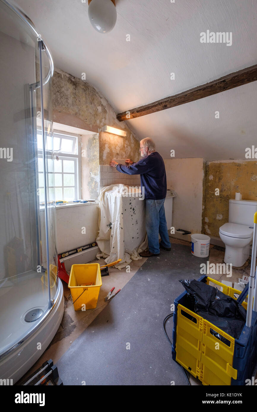 Pensionné homme innewly avec de nouvelles tuiles de décoration salle de bains équipé dans le vieux chalet, Gloucestershire, Angleterre, Royaume-Uni Banque D'Images