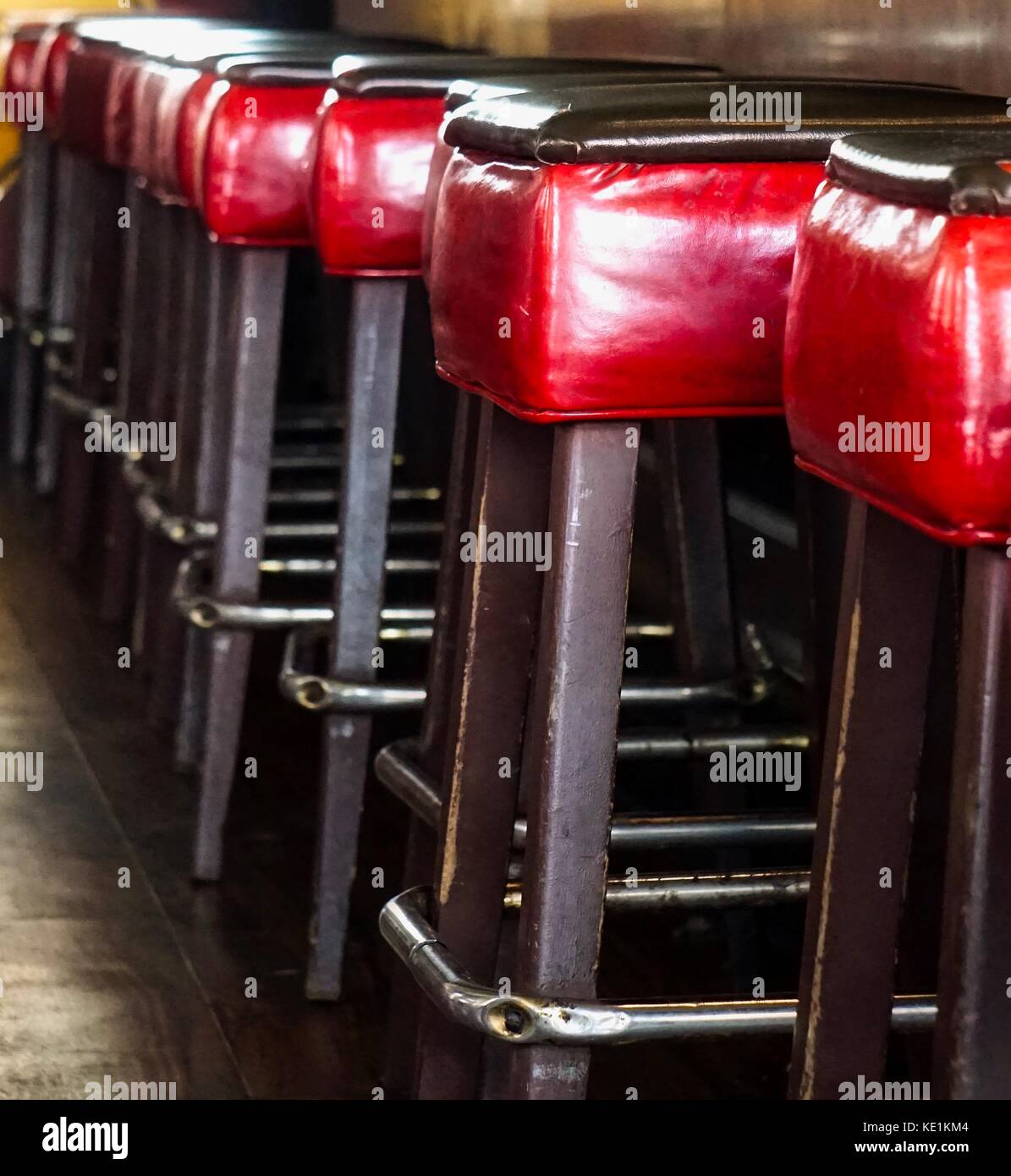 Tabourets en cuir rouge vide alignés dans une rangée au comptoir Banque D'Images