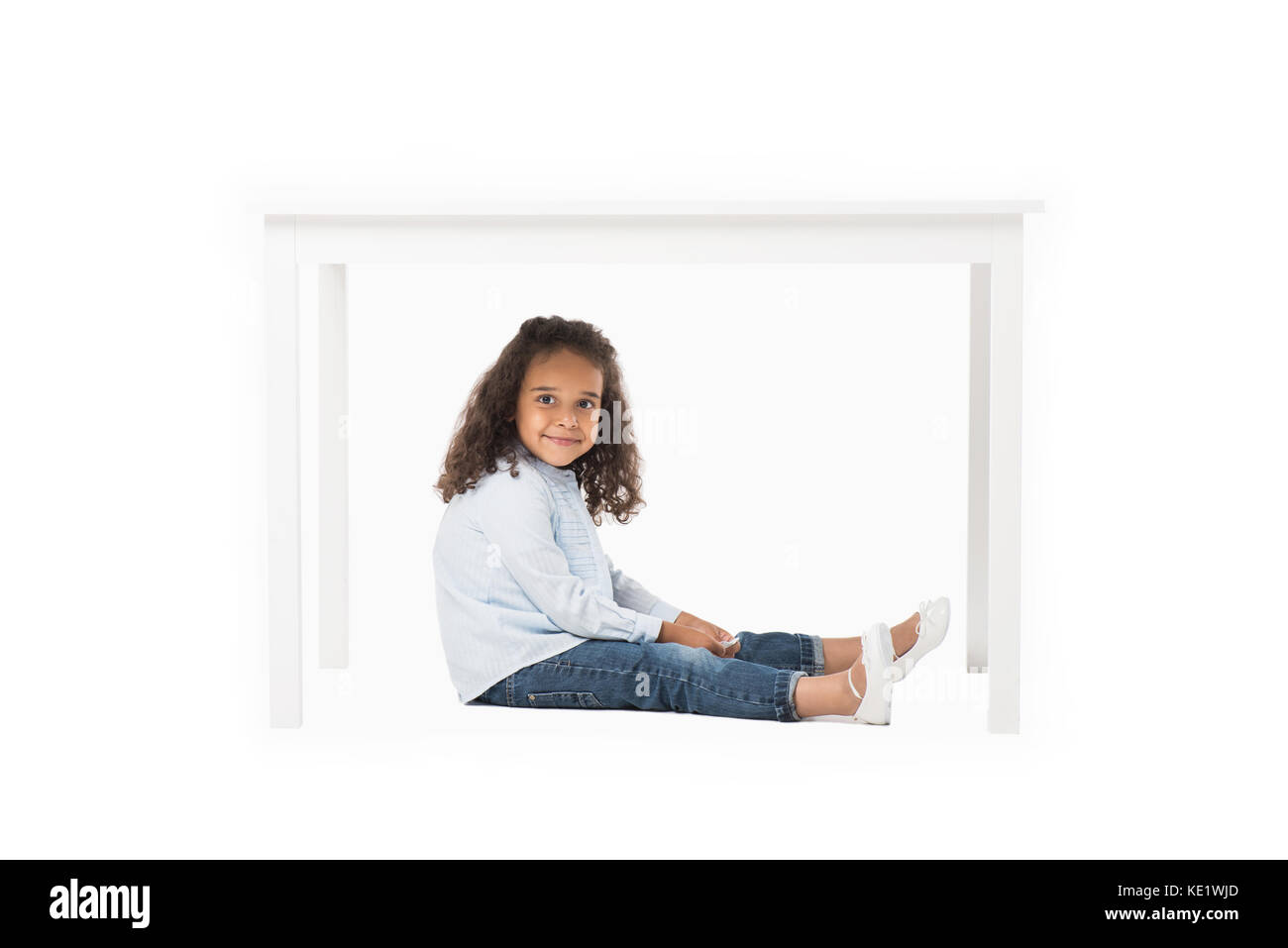 Adorable african american girl sitting sous table isolated on white Banque D'Images