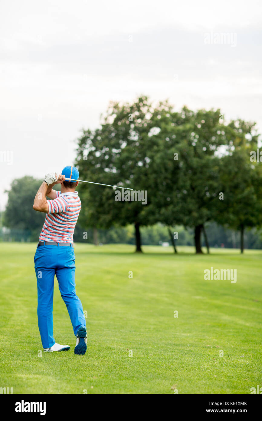 Jeune homme jouant au golf sur une journée ensoleillée sur un magnifique parcours de golf Banque D'Images