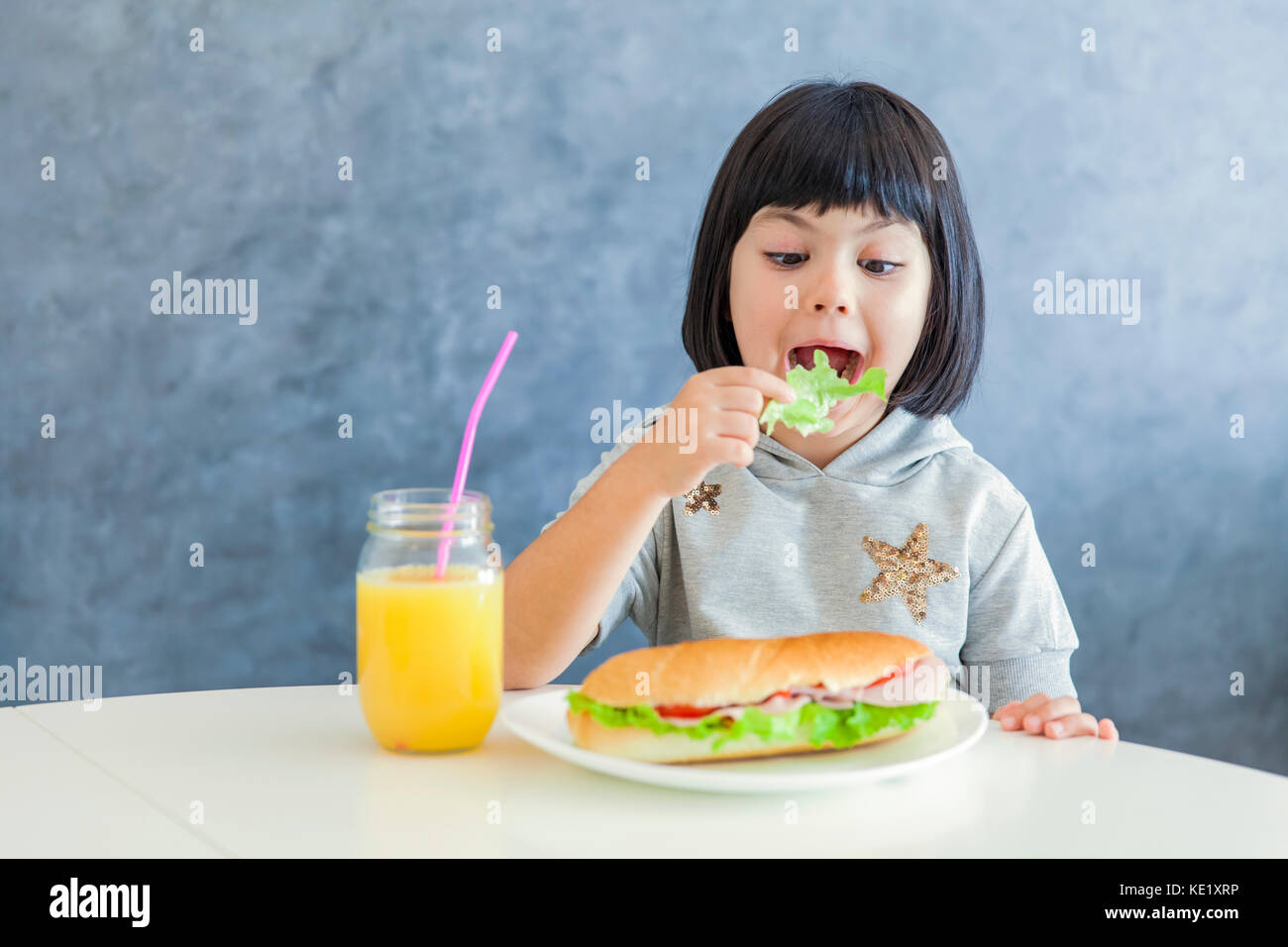 Cute black hair girl eating la laitue et le petit-déjeuner Banque D'Images