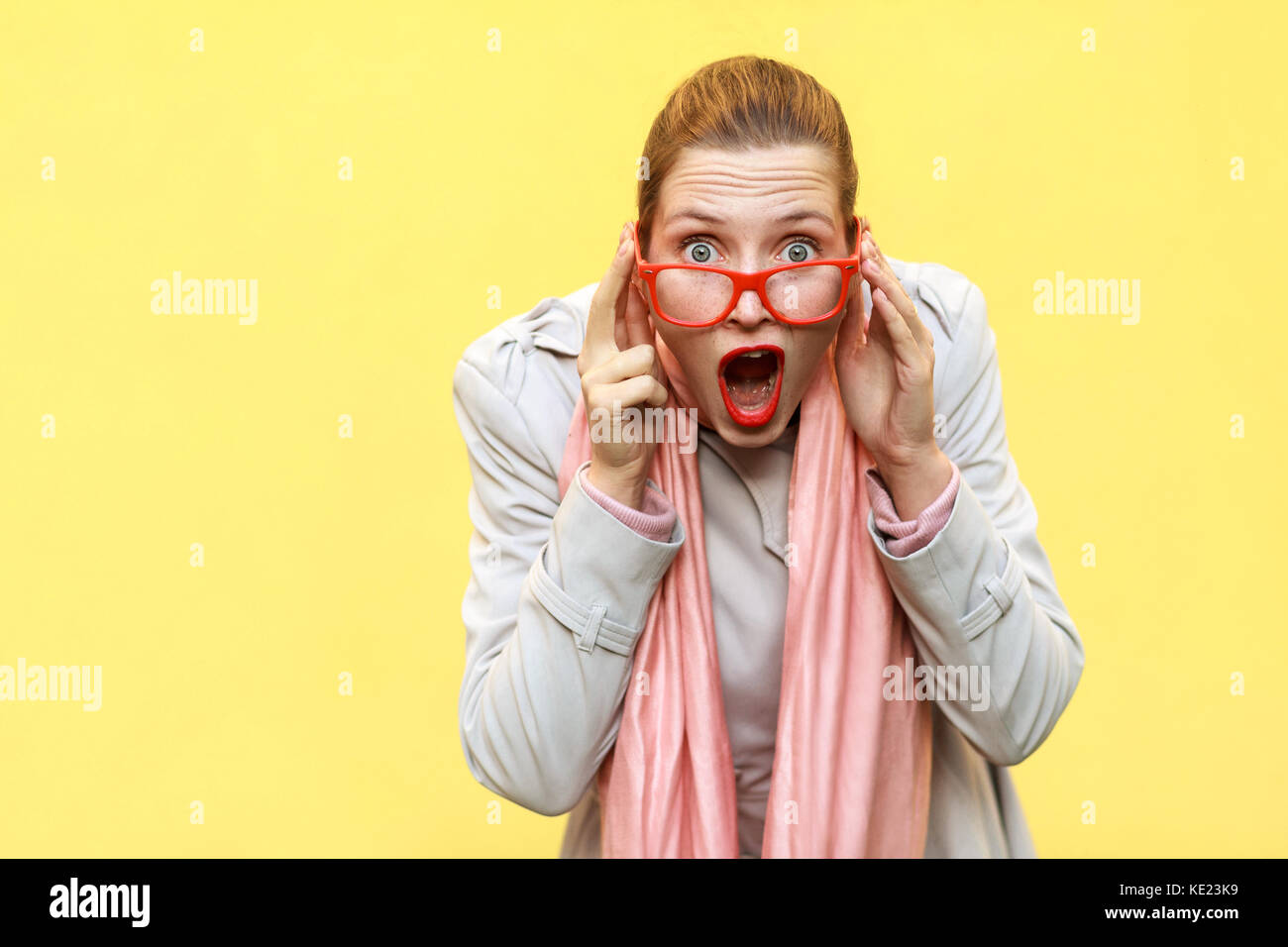 Choqué femme portant manteau, écharpe rose, l'ouverture de bouche , ayant surpris choqué face. studio shot Banque D'Images
