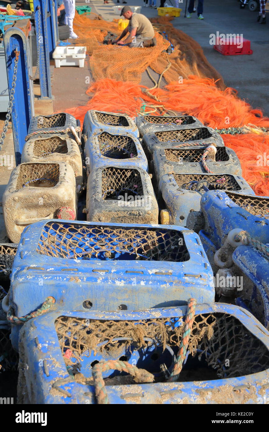 Whitstable, uk - 15 octobre 2017 : les boîtes de pêche colorés et des filets de pêche avec un pêcheur travaillant sur ses filets dans l'arrière-plan Banque D'Images