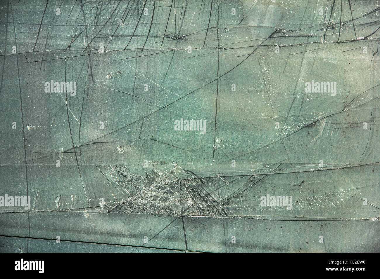 Feuille de verre cassé, endommagé avec fissures noires sur fond vert Banque D'Images