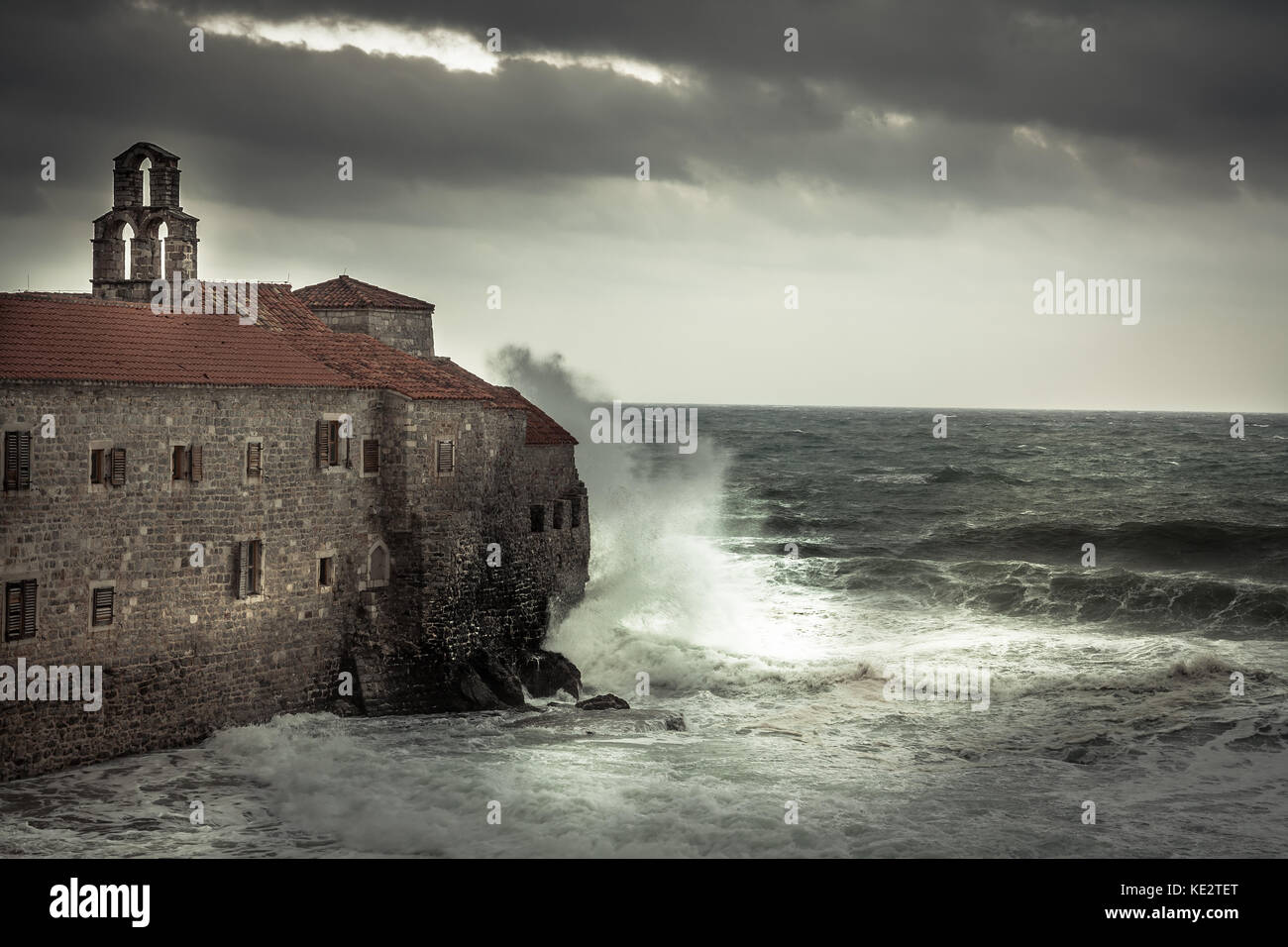 Avec de grandes vagues de tempête orageuse au littoral s'écraser sur les murs d'un château médiéval sur mer terre et ciel dramatique sombre dans la saison d'automne sur le coût de la mer Banque D'Images