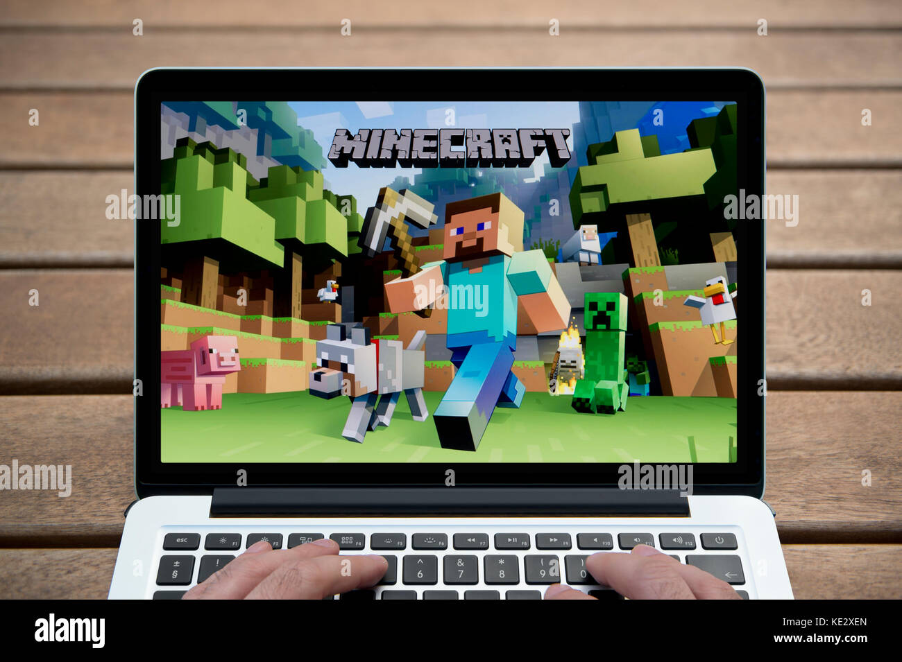 Le jeu Minecraft sur l'écran d'un ordinateur portable MacBook Pro, tourné contre un banc en bois fond de plein air y compris les doigts d'un homme (rédaction uniquement) Banque D'Images