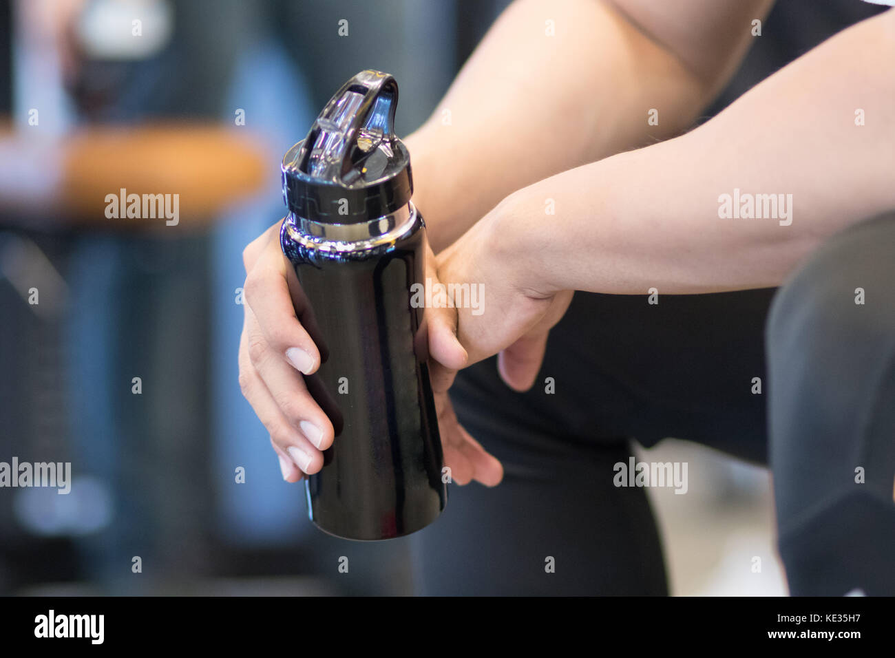 Jeune homme tenir bouteille d'eau potable dans le centre de remise en forme de l'athlète masculin. soif après une formation dans une salle de sport. sporty asiatique de prendre une pause de travailler Banque D'Images