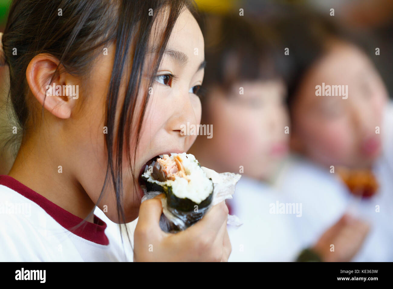 Un gamin d'école primaire japonais qui mange dans la salle de classe Banque D'Images