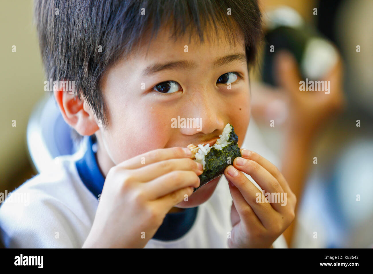 Un gamin d'école primaire japonais qui mange dans la salle de classe Banque D'Images