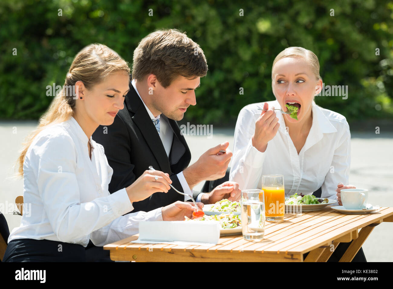 Les jeunes hommes et femmes d'affaires heureux de manger de la nourriture dans le restaurant Banque D'Images