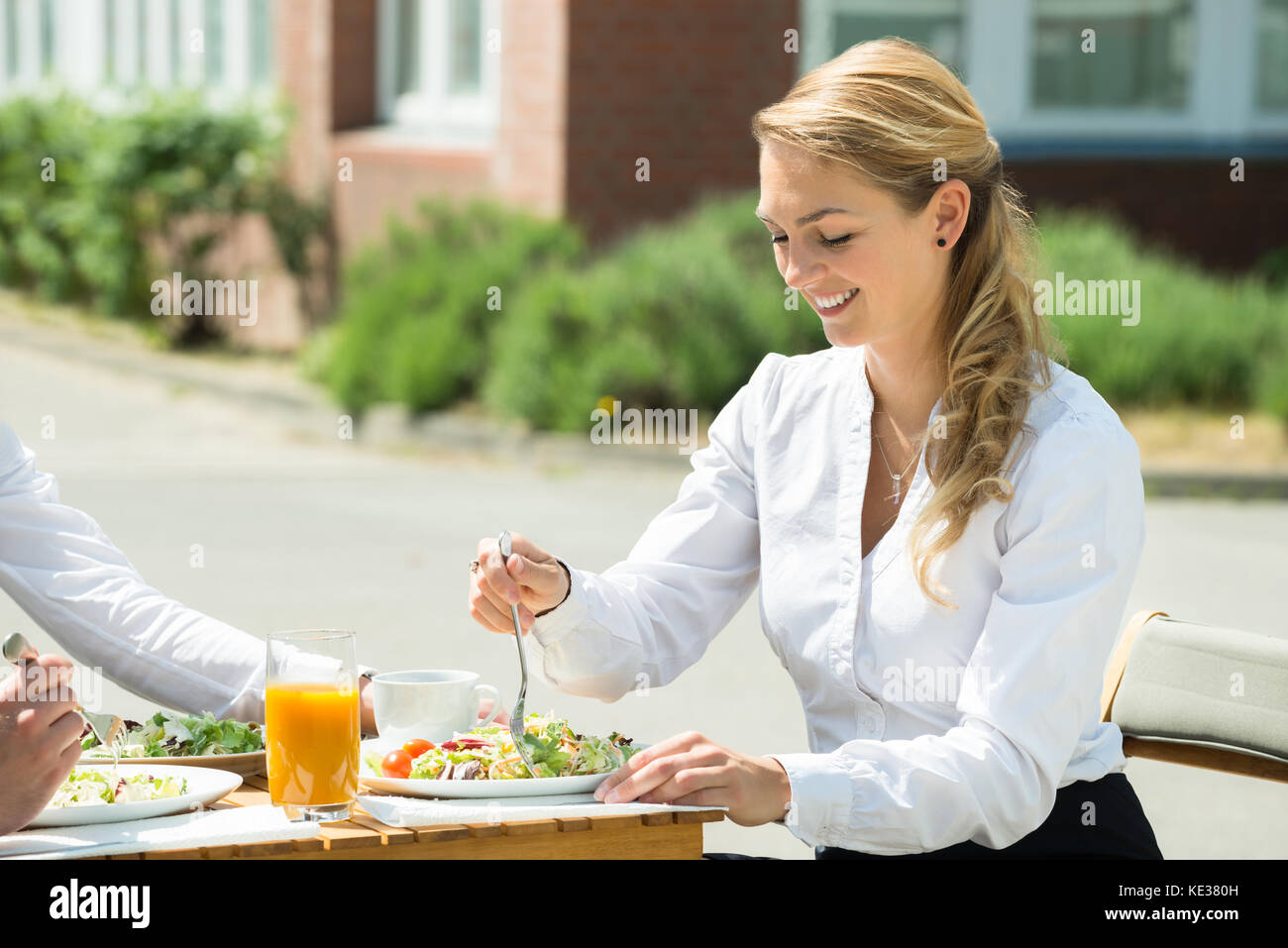 Happy young woman eating food in restaurant Banque D'Images