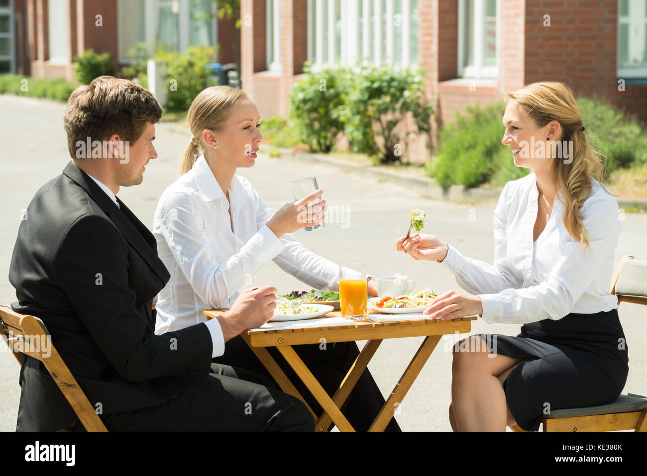 Heureux les jeunes gens d'affaires, hommes et femmes de manger de la nourriture dans le restaurant Banque D'Images