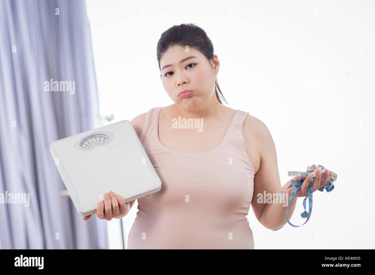 Portrait de jeune femme obèse avec une échelle et ruban à mesurer Banque D'Images