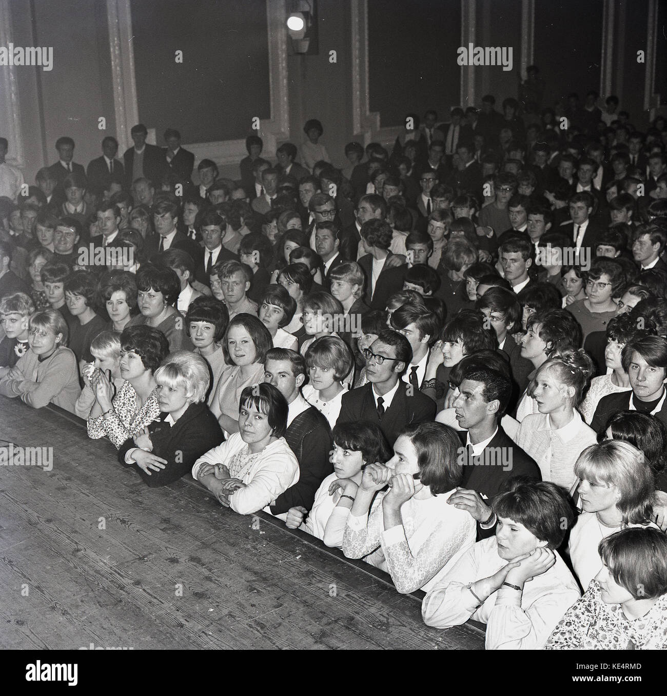 1964, historiques, l'BAH, Aylesbury voit un des jeunes adultes, surtout les jeunes femmes debout, en appui sur l'avant de la scène en bois, en anticpation de l'exécution musicale, England, UK. Banque D'Images