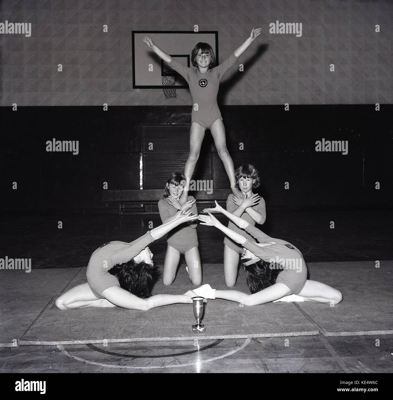 Des années 1960, une photo à partir du milieu des années 60 des cinq jeunes femmes gymnastes artistiques montrant outre de leurs talents dans la salle de sport et l'école avec un trophée qu'ils ont gagné sur le tapis en face d'eux, England, UK. Banque D'Images