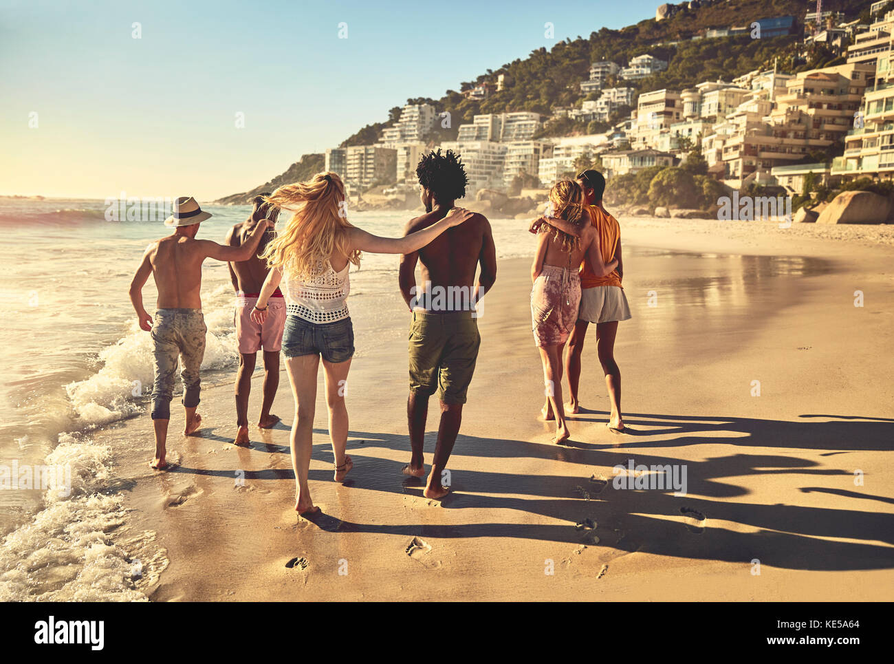 Des jeunes amis en couple marchent sur la plage ensoleillée d'été Banque D'Images