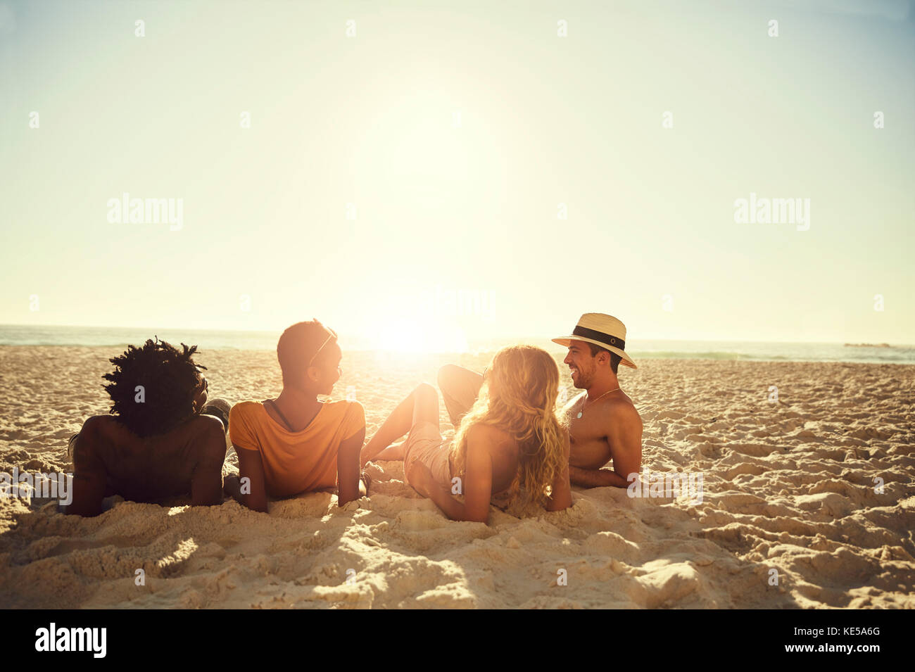 Les jeunes couples se pondent, se détendent sur la plage ensoleillée d'été Banque D'Images