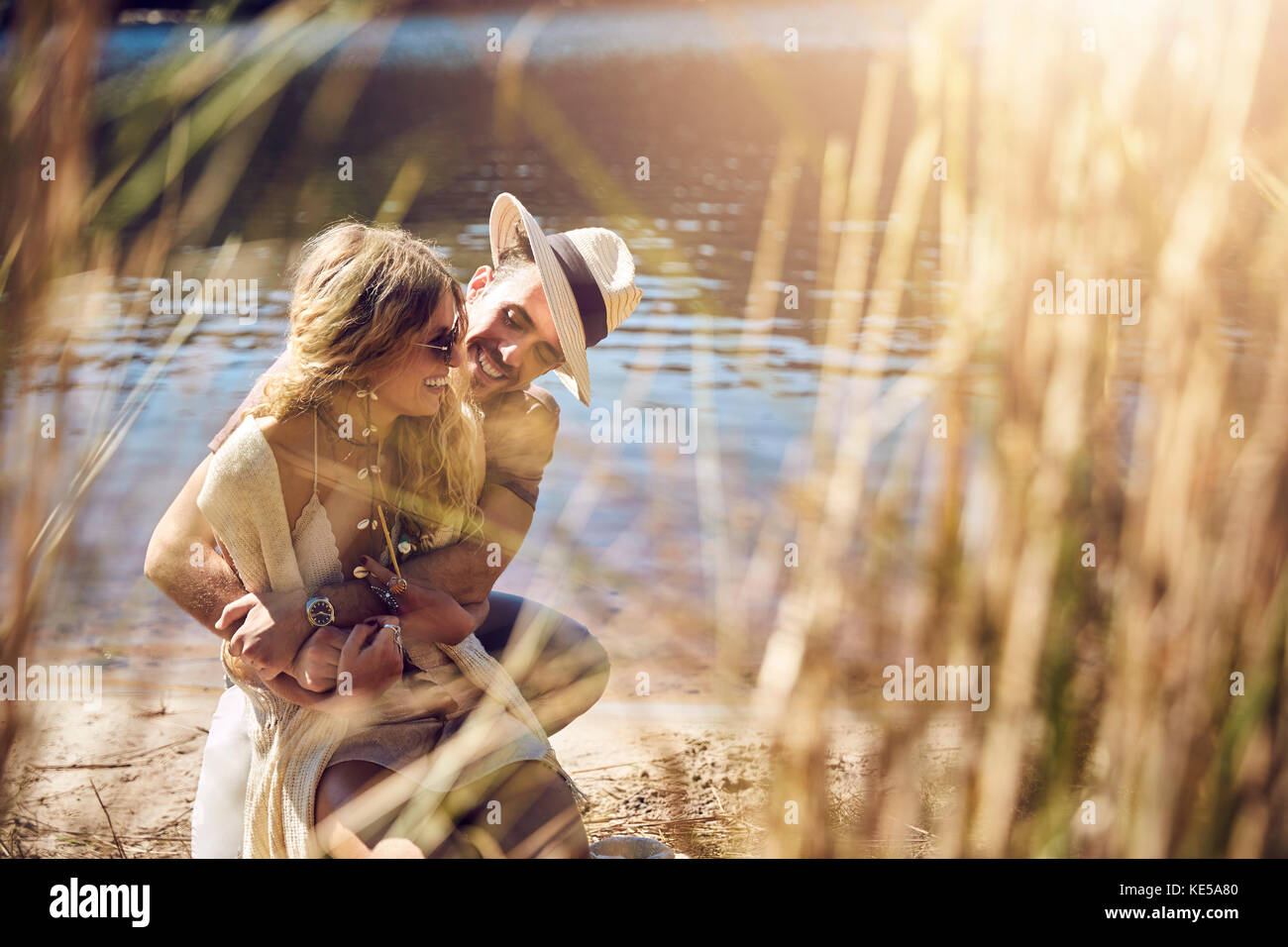 Un jeune couple affectueux qui s'enserre au bord de la rivière ensoleillée en été Banque D'Images