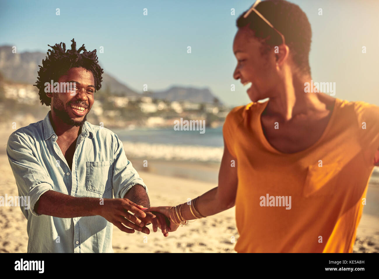 Jeune couple joueur tenant la main sur la plage ensoleillée d'été Banque D'Images